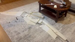3D-printed wing panels, center-section frame and control surfaces laid out on a rug with long dark rods fitted between them